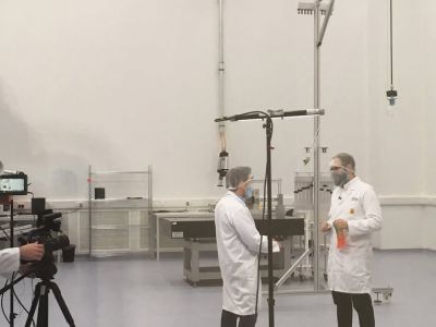 Two people in lab coats being filmed in a laboratory environments